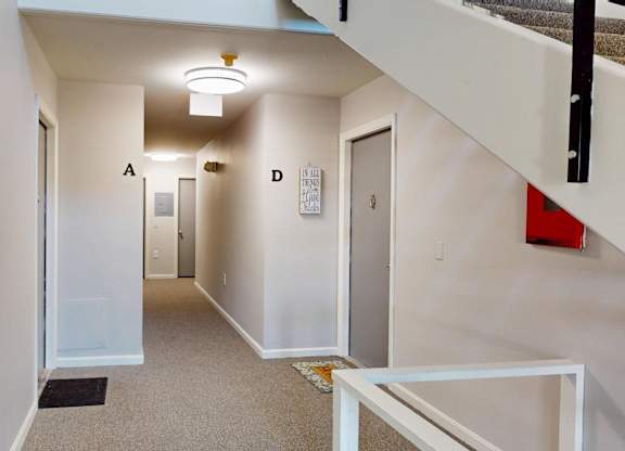A hallway with a white door on the left and a red object on the right.