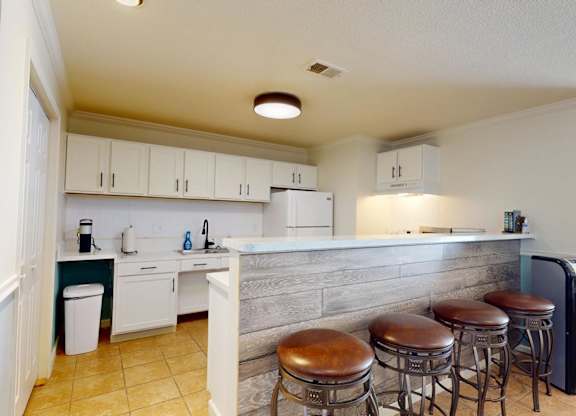 A kitchen with white cabinets and a grey counter.