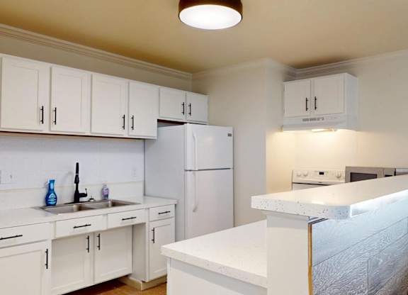 A kitchen with white cabinets and appliances.