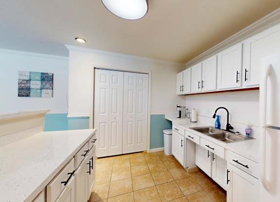 A kitchen with white cabinets and a white fridge.