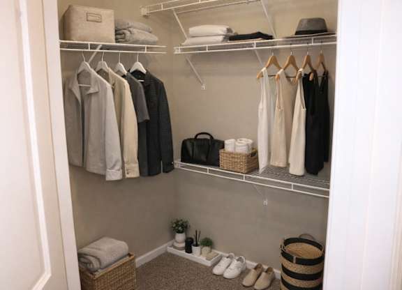 A closet with clothes and shoes neatly organized.