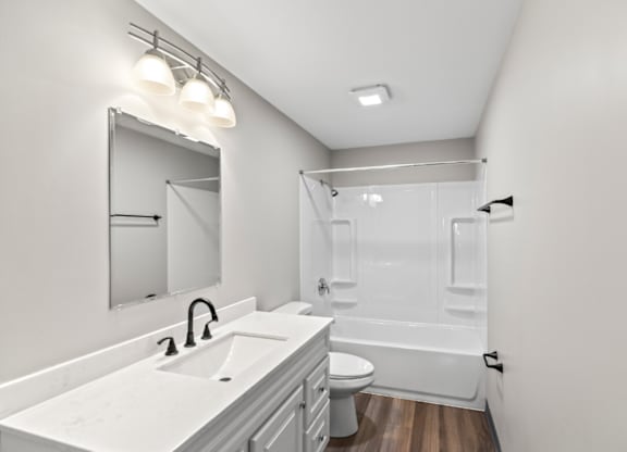 A white bathroom with a sink, mirror, and toilet.