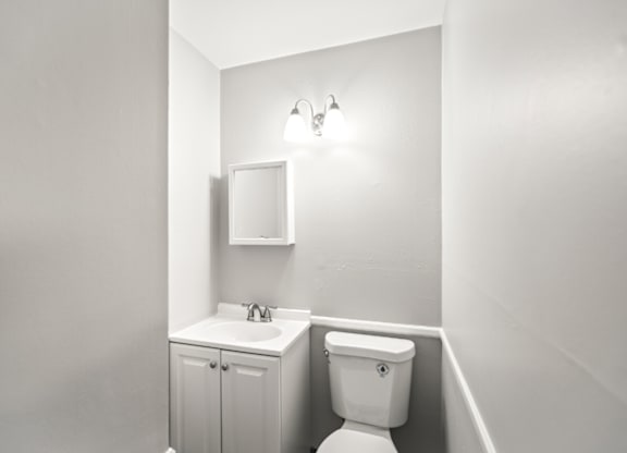 A white bathroom with a toilet, sink, and medicine cabinet.