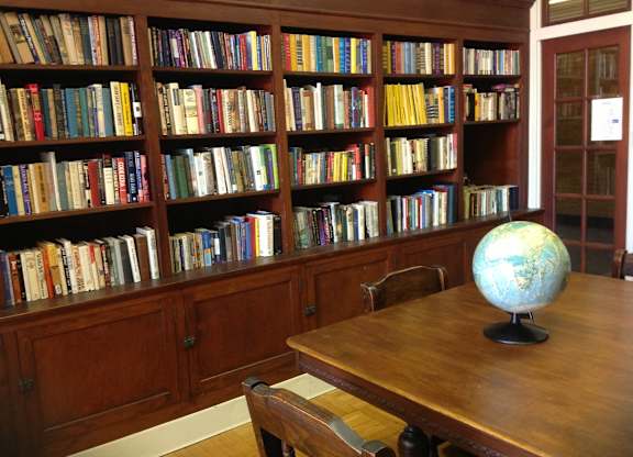 A room with a bookshelf filled with books and a globe on the table.