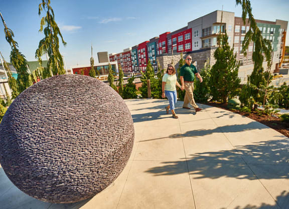 a man and a woman walking past a large sphere sculpture