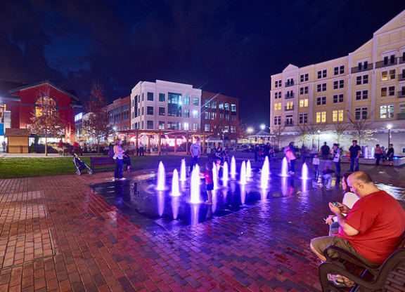 a man sitting on a bench in front of a fountain