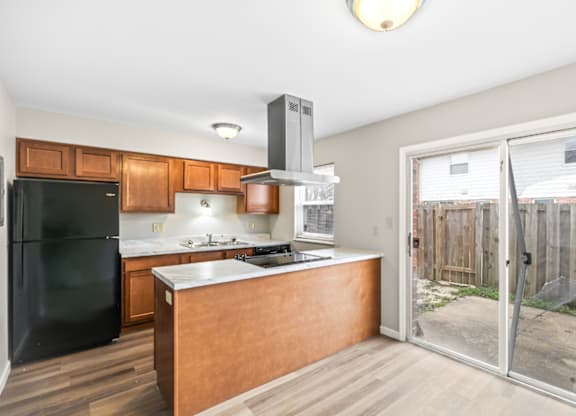 A kitchen with a black fridge and wooden cabinets.