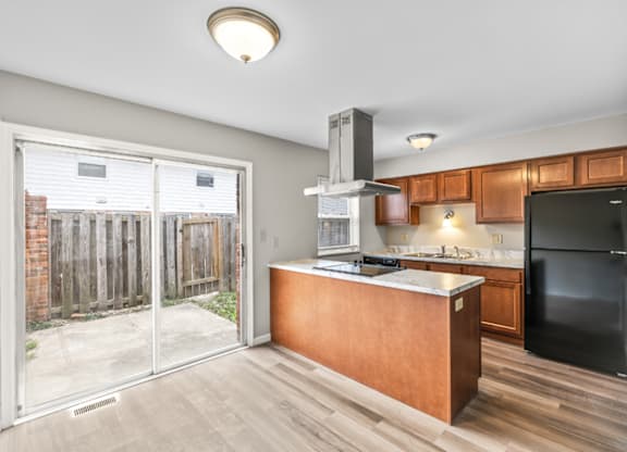 A kitchen with a black refrigerator and wooden cabinets.