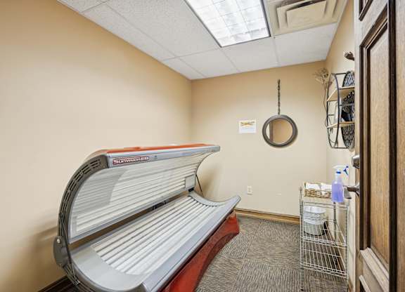 A tanning bed is in a room with a mirror on the wall.