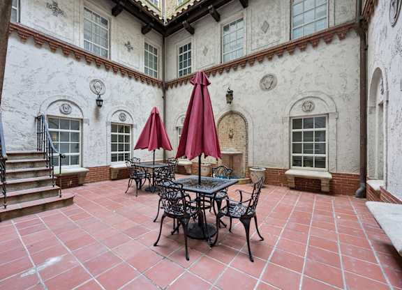 A patio with a table and chairs under red umbrellas.