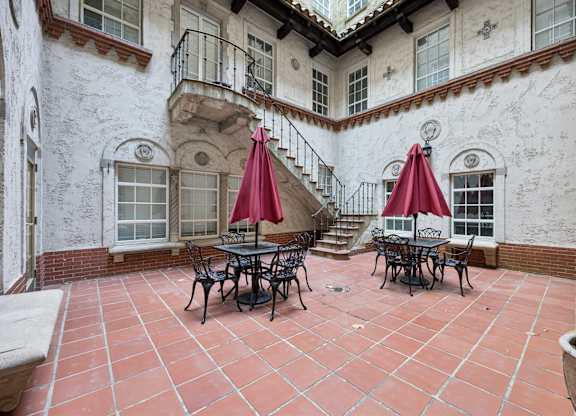 A patio with a table and chairs and umbrellas.