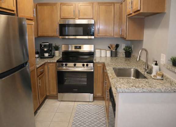 A kitchen with a stainless steel refrigerator, microwave, oven, and sink.