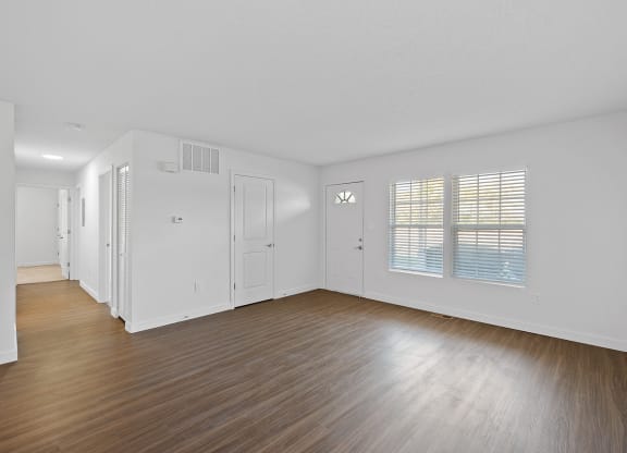 an empty living room with wood floors and white walls