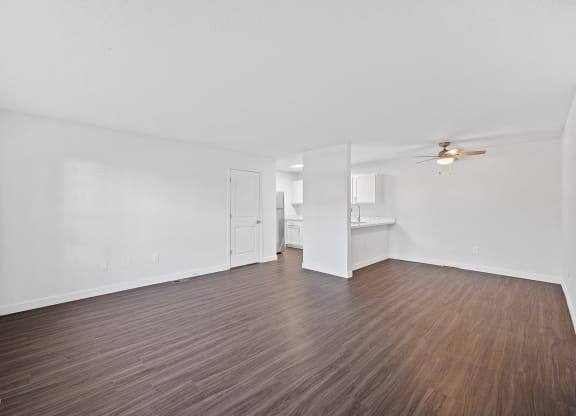 the living room of an apartment with wood flooring and a ceiling fan