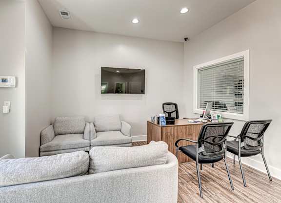 A modern living room with a grey couch, a white chair, and a wooden desk. at The Apex, Cincinnati