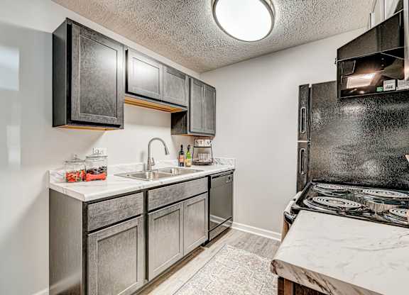 A kitchen with a black stove top oven and a white sink. at The Apex, Cincinnati, 45239