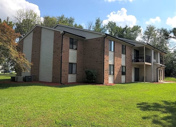 a brick apartment building with a grassy yard