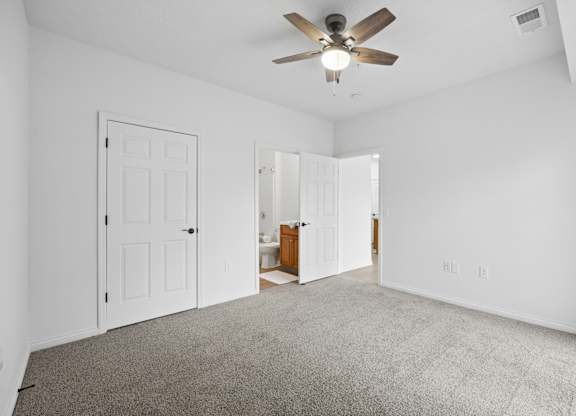 A room with a ceiling fan and carpeted floor.