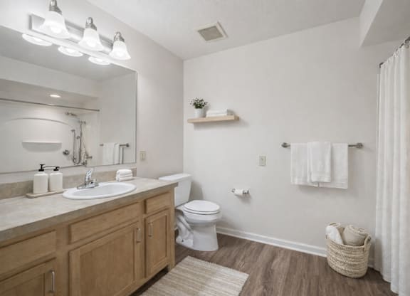 A bathroom with a white sink, toilet, and a white shower curtain.