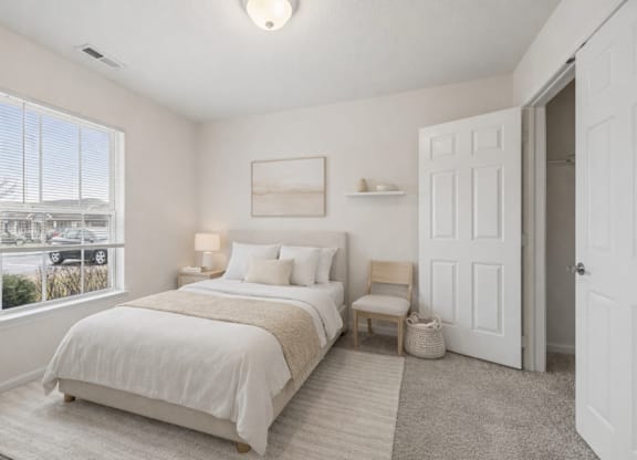 A bedroom with a large bed and a window overlooking a parking lot.