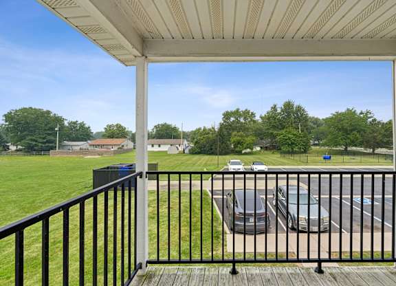 A balcony with a black railing overlooks a parking lot.