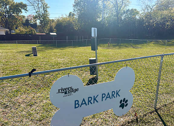 A sign for Bark Park is displayed in front of a fence.