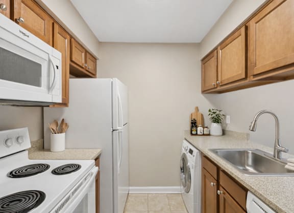 A kitchen with white appliances and wooden cabinets.