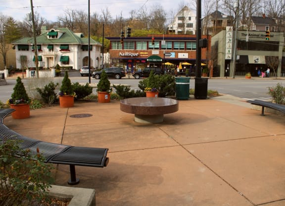a park with benches and a stone table on a city street