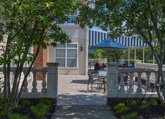 a patio with tables and chairs and a blue umbrella in front of a building at Bishops Gate, Cincinnati, OH