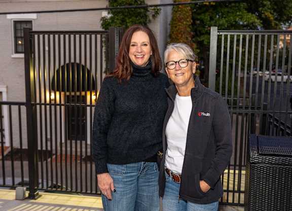 two women standing next to each other in front of a fence at Roebling Row, Kentucky