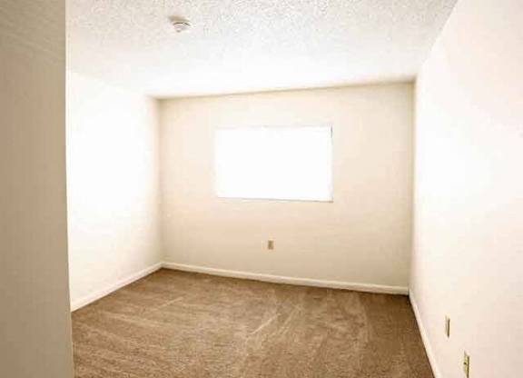 A room with a window and carpeted floor.