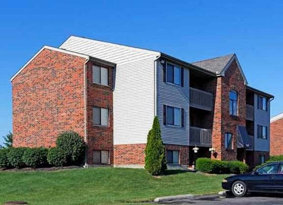A black car is parked in front of a two-story apartment building.