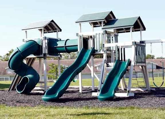 A playground with a green slide and a white and green structure.