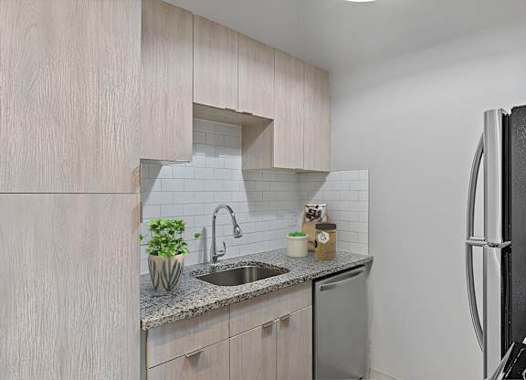 A kitchen with a sink, a refrigerator, and a counter with a potted plant on it. at The Reserve at Grand Valley Apartments, Ohio