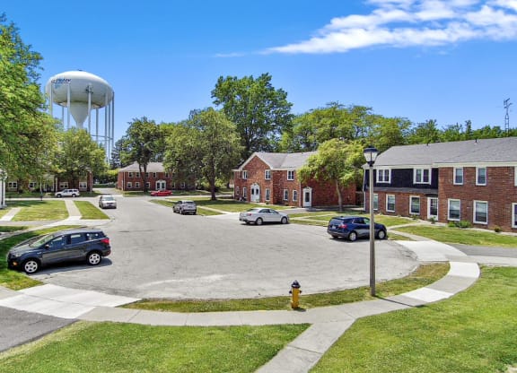 a parking lot in front of a brick building with a water tower in the background