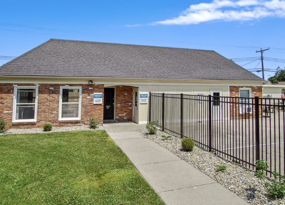 a small brick building with a black fence in front of it