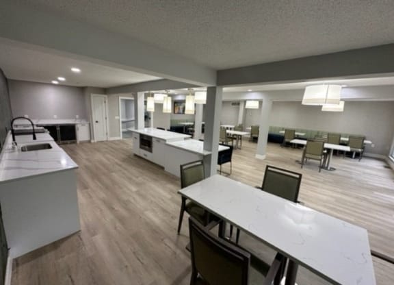 a large room with tables and chairs and a kitchen