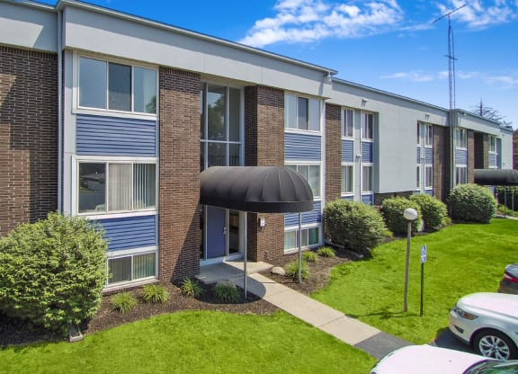 a brick apartment building with blue shutters and a green lawn
