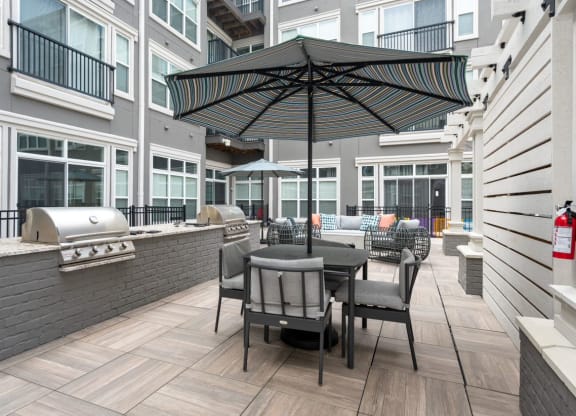 a patio with a grill and umbrella at the bradley braddock road station apartments