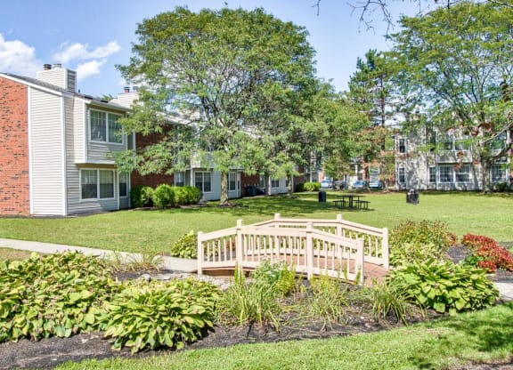 a small wooden bridge crosses a grassy area in front of a brick building at The Berryessa Apartments, Ohio, 98104
