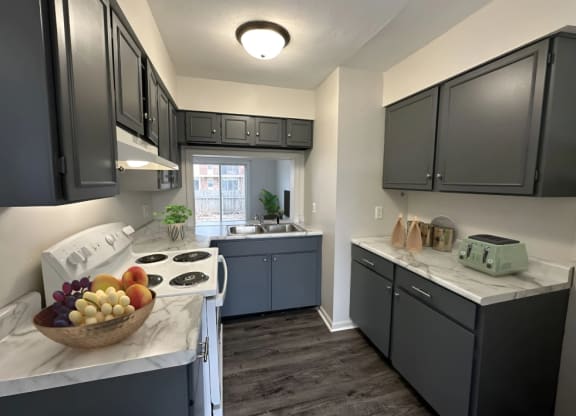 a kitchen with gray cabinets and a bowl of fruit on the counter