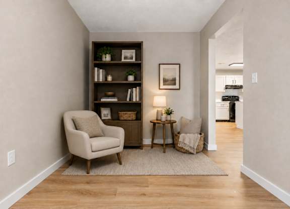 A living room with a chair, a table, and a bookshelf.