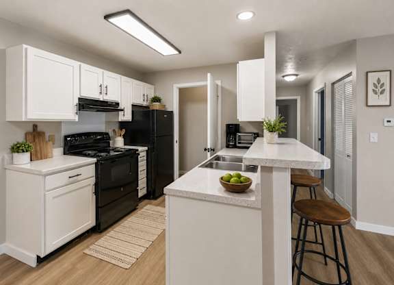 A modern kitchen with black appliances and white cabinets.