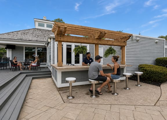A group of people are sitting at a bar on a patio.