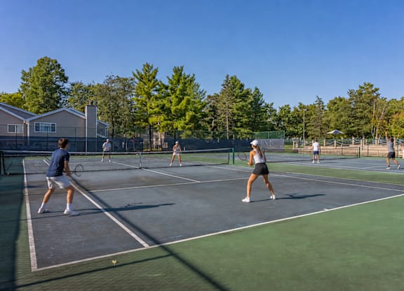 A group of people playing tennis on a court.