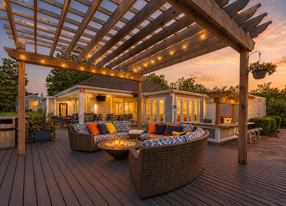 A wooden deck with a pergola and outdoor furniture.