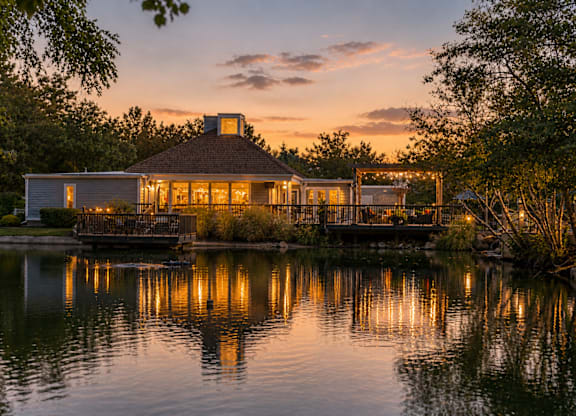 A house with a gazebo is reflected in a body of water.