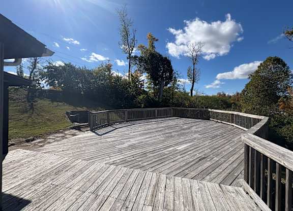 A wooden deck overlooks a grassy area with trees.