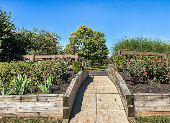 A wooden bridge leads to a lush garden.