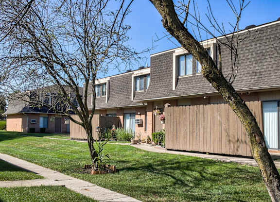 A tree in front of a building with a brown roof.